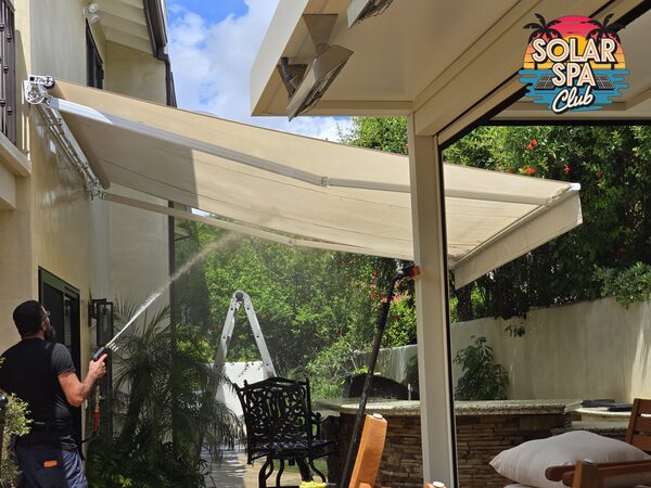 Technician softwashing a retractable patio awning