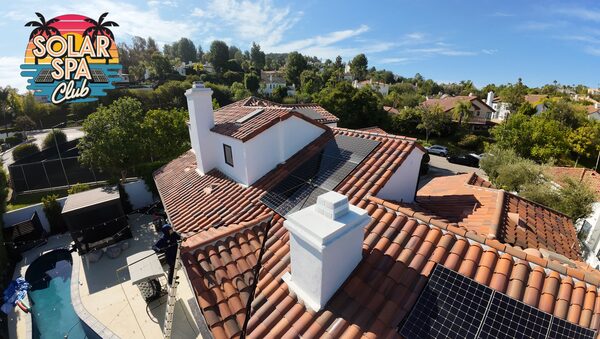 Aerial view of a technician on a ladder cleaning solar panels on a terracotta tile roof